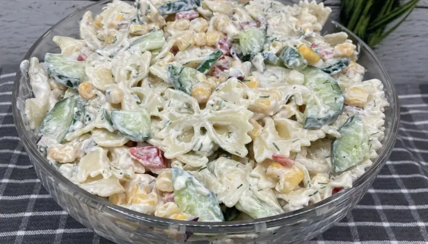 Pyszna, kremowa najlepsza sałatka z makaronem farfalle, ogórkiem, kukurydzą i ziołami.