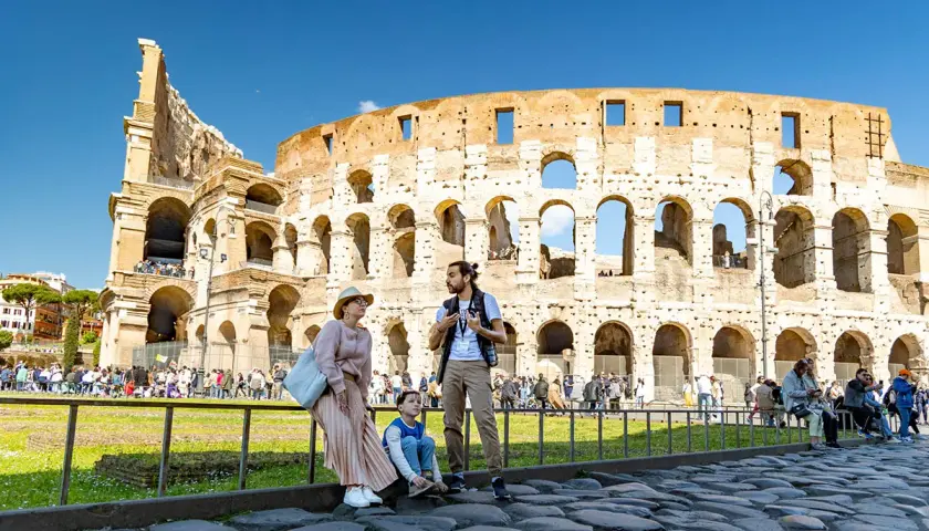 Famille admirant l'imposante arène de Rome, le Colisée, sous un ciel bleu éclatant.