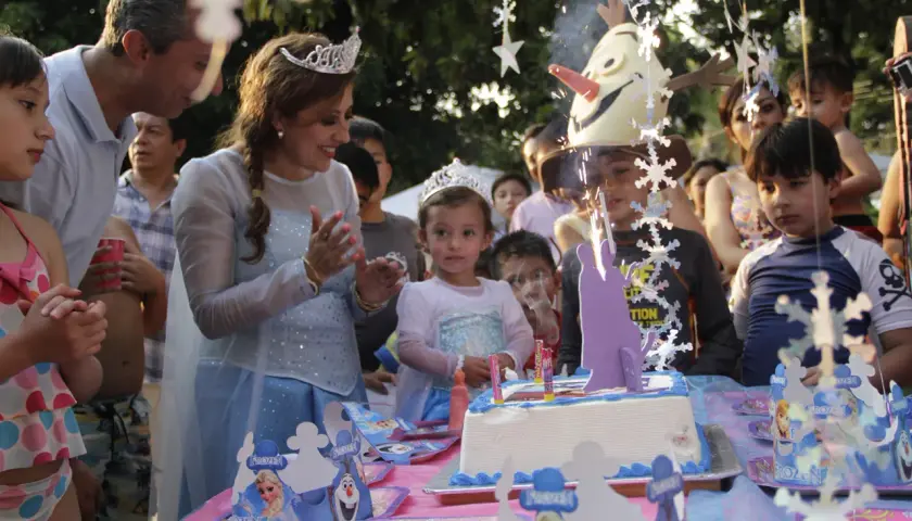 Celebración de cumpleaños en aula infantil con pastel de Frozen y niños emocionados.