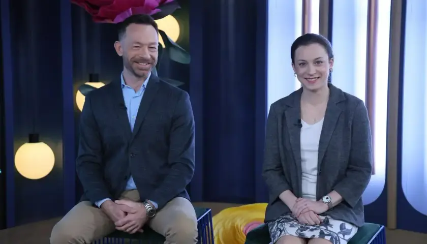 Tomasz Wasilewski i kobieta siedzą na kanapie w studiu telewizyjnym.
