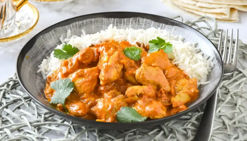 Un delicioso pollo tikka masala receta servido con arroz basmati y cilantro fresco.