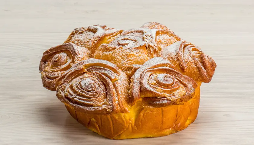 Una torta delle rose dorata e soffice, cosparsa di zucchero a velo, pronta per essere gustata.