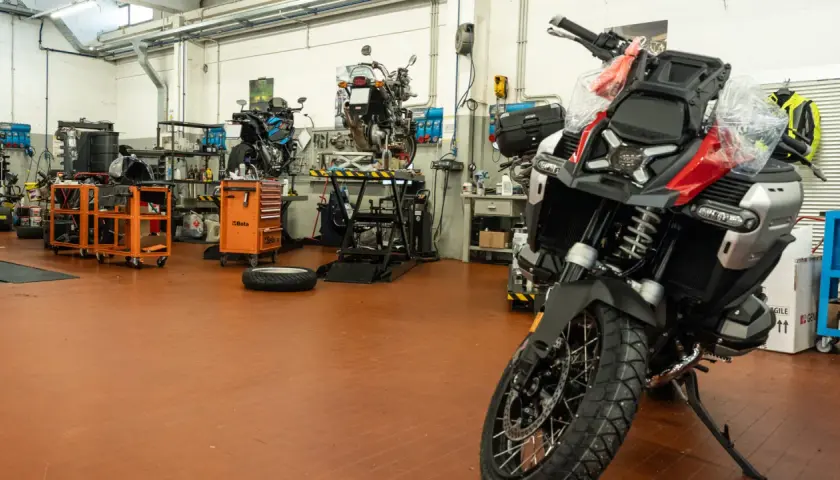 Officina moto con diverse moto in lavorazione. Un tecnico si chiede ogni quanto si fa il tagliando per mantenere al meglio il proprio mezzo.