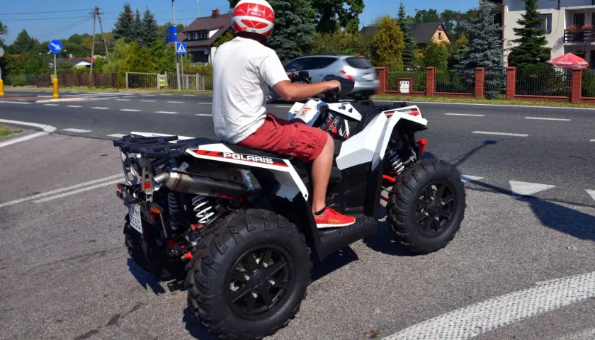 Mężczyzna w kasku na quadzie Polaris na drodze. Czy na quadzie trzeba mieć kask? Tak, dla bezpieczeństwa!