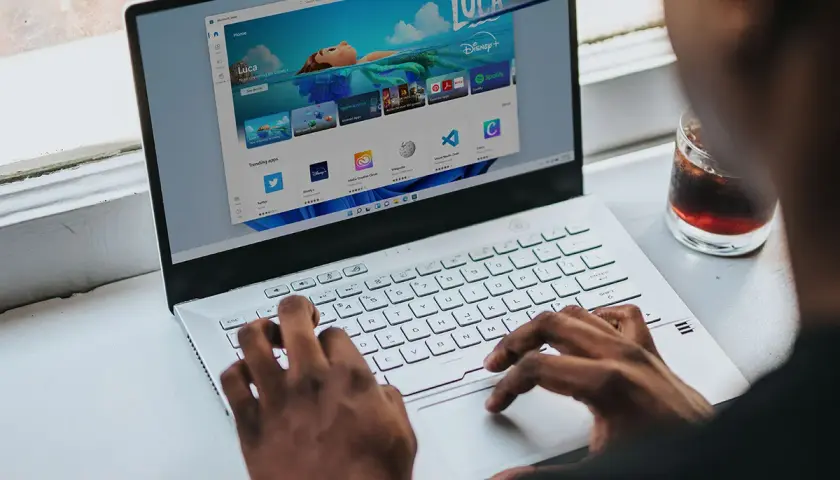 Osoba korzysta z laptopa z systemem Windows 11, przeglądając sklep z aplikacjami. Czy Windows 11 jest darmowy? Sprawdźmy!
