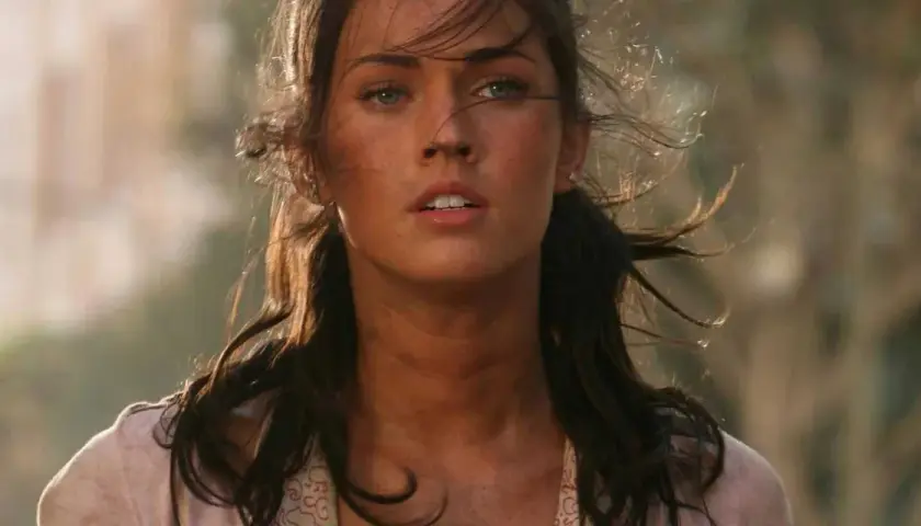 Megan Fox i en dramatisk scen från en av hennes filmer. Hennes hår blåser i vinden och hon ser ut att vara mitt i en actionfylld sekvens.