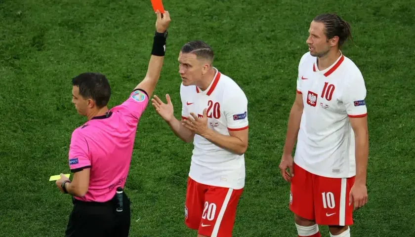 Sędzia pokazuje czerwoną kartkę, co oznacza koniec gry dla zawodnika.