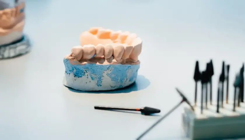 Model szczęki, na którym powstaje proteza elastyczna, obok narzędzi dentystycznych.