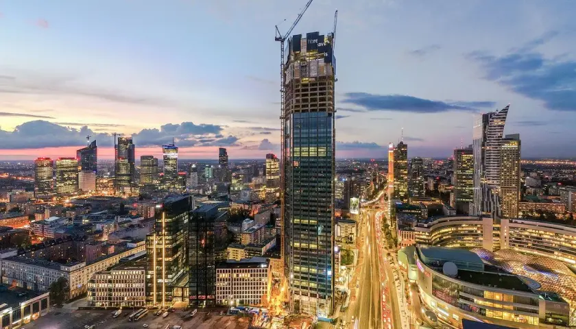 Warszawski drapacz chmur w budowie, Varso Tower, z pewnością będzie miał wiele metrów wysokości. W tle widać panoramę miasta o zmierzchu.