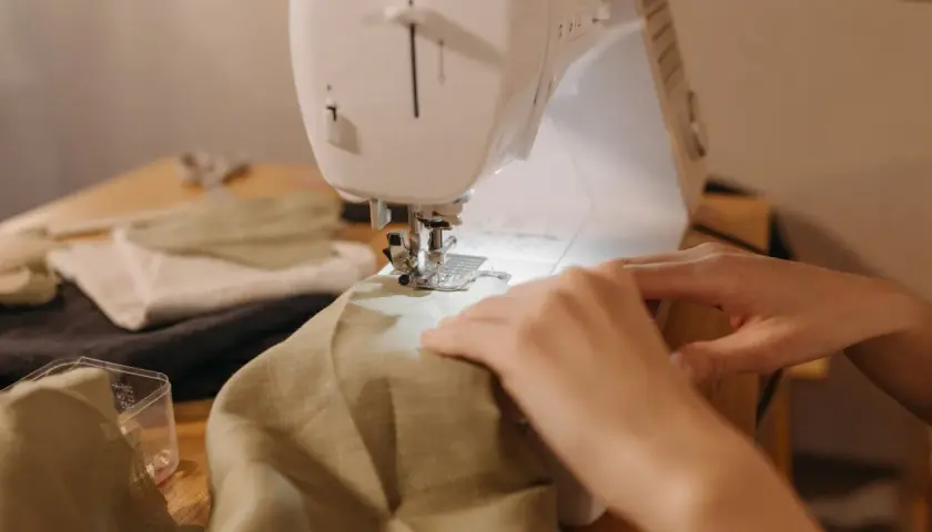 Hands guide fabric through a sewing machine, a peaceful scene of a sewing hobby.