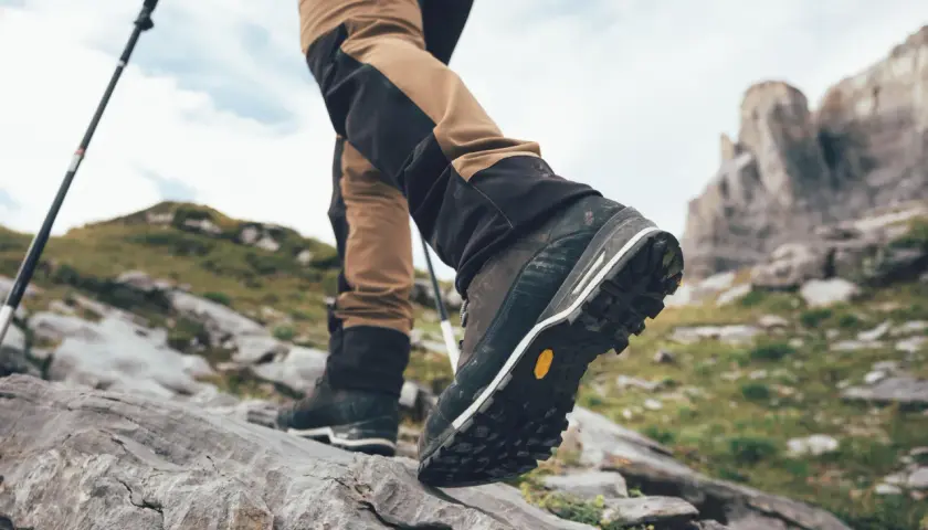Turysta stawia kroki na kamienistym szlaku, jego buty z podeszwami Vibram zapewniają pewność na nierównym terenie.
