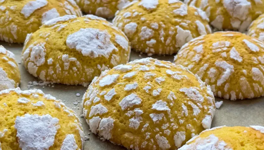 Popękane ciasteczka cytrynowe, posypane cukrem pudrem, wyglądają jak małe, słodkie śnieżki.
