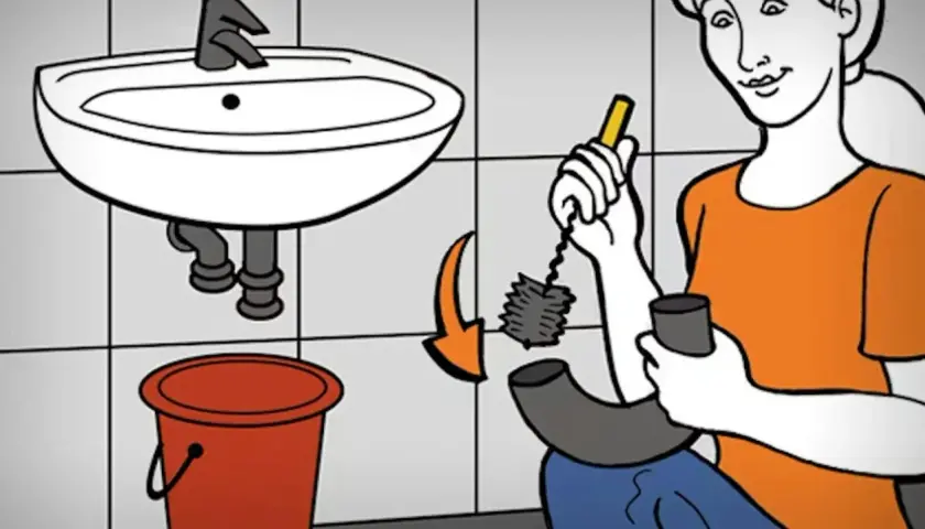 Kobieta czyści zatkany zlew. Trzyma szczotkę do rur i wiadro.