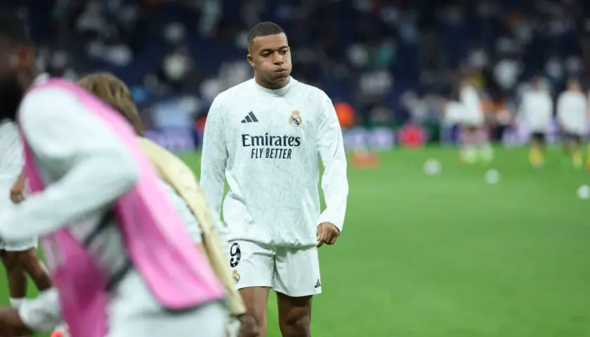 Mbappé, młody piłkarz Realu Madryt, w białej koszulce treningowej z logo Emirates.