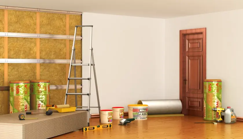 Materiali per isolamento termico e acustico, inclusi rotoli di lana minerale per un efficace cappotto interno antimuffa. Attrezzi da lavoro e pannelli pronti per l'installazione.