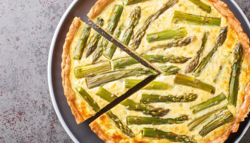 Eine köstliche Spargel Quiche mit einem goldbraunen Teigrand und saftiger Füllung, belegt mit frischem Spargel.