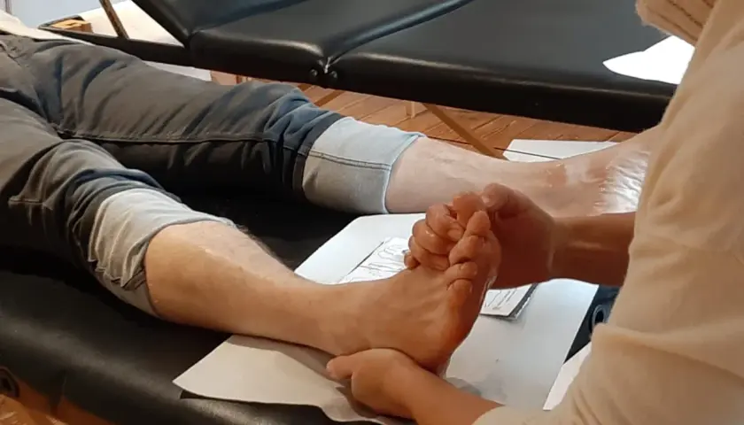 A person's foot is being massaged by another person's hands.