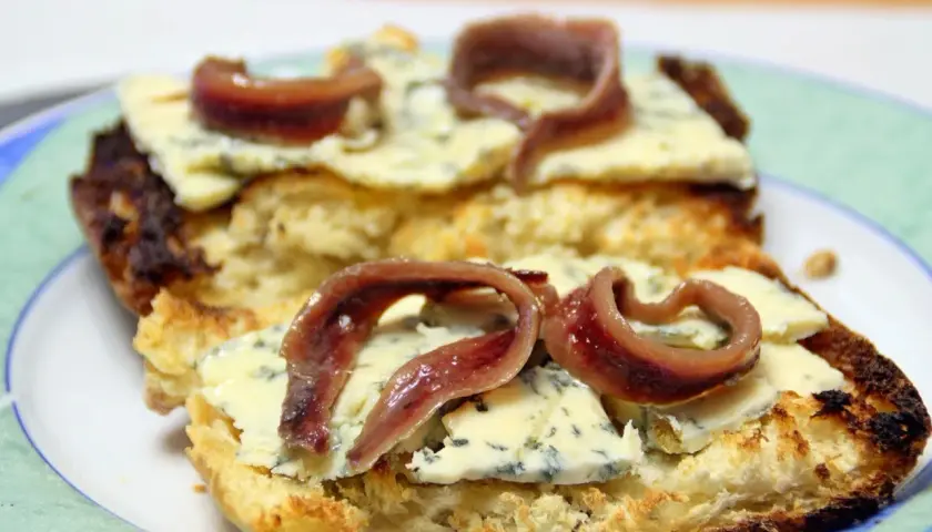 Tostada con queso azul y anchoas. Una combinación deliciosa que responde a la pregunta: ¿qué queso combina con anchoas?