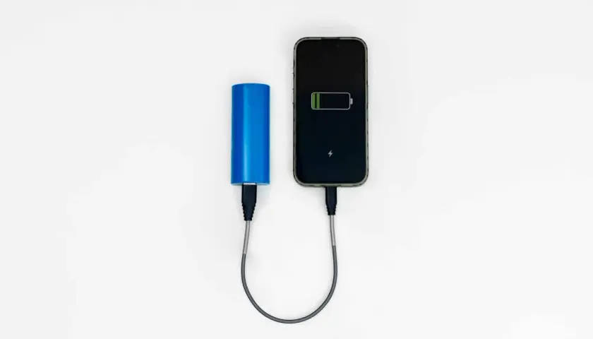Niebieski powerbank Wizzair ładuje smartfon.
