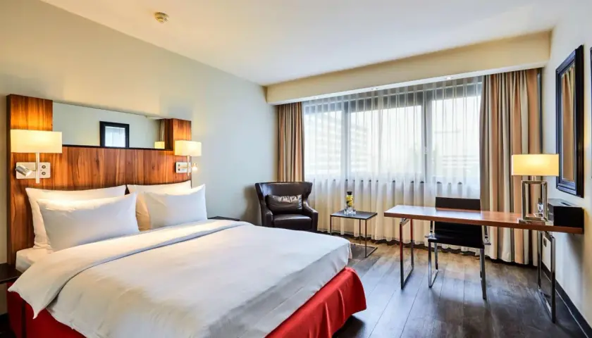 Przytulny pokój w hotelu Radisson Blu Scandinavia Hotel Dusseldorf z wygodnym łóżkiem, fotelem i biurkiem.