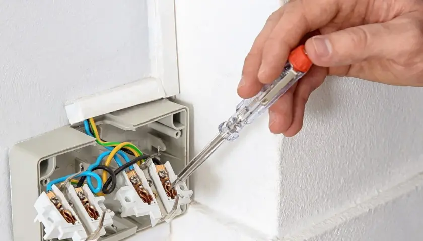Ręka trzyma próbnik napięcia, sprawdzając instalację elektryczną. Tak działa próbnik napięcia, pomagając w bezpiecznym montażu.