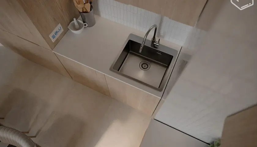 Nowoczesny zlew kuchenny podblatowy ze stali nierdzewnej, idealnie wkomponowany w blat. Obok moździerz i drewniane akcesoria.