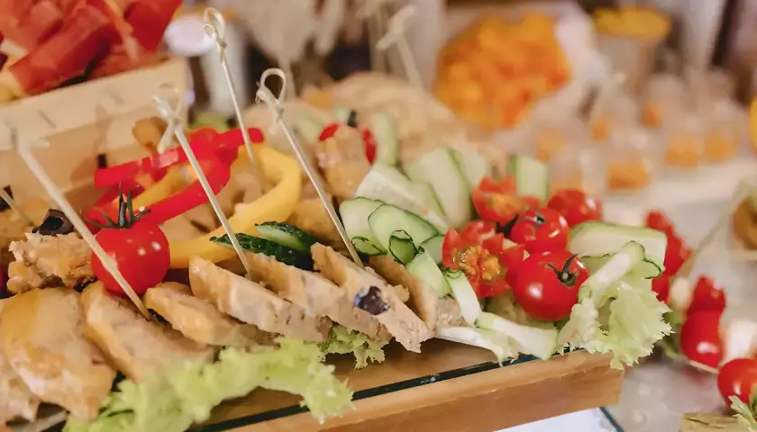 Un buffet froid festif pour un buffet départ retraite : brochettes de tomates cerises, concombres, poivrons et tranches de pain garnies.