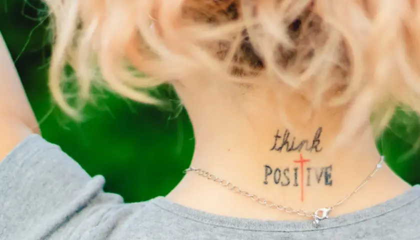 Mądre cytaty na tatuaż: "think POSITIVE" wytatuowane na karku, przypomina o pozytywnym nastawieniu.