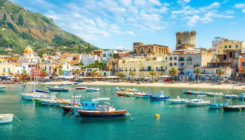 Un borgo marinaro con case colorate, una torre antica e barche nel mare cristallino. Un tuffo nella Ischia storia e bellezza.
