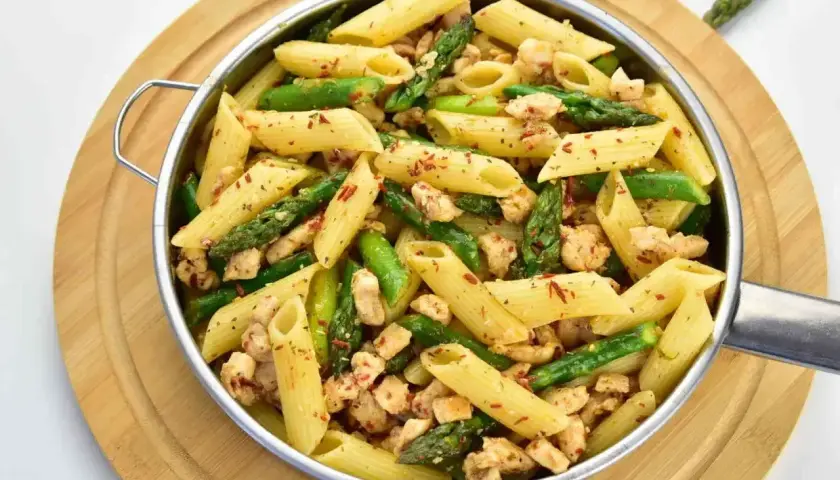Penne z kurczakiem i szparagami, posypane papryką. Pyszne danie, które zachwyci każdego smakosza.