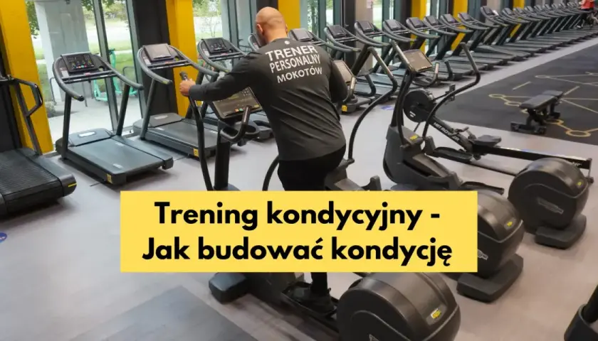 Mężczyzna w koszulce "Trener Personalny Mokotów" ćwiczy na orbitreku. W tle bieżnie i wioślarze, idealne do treningu wytrzymałościowego.