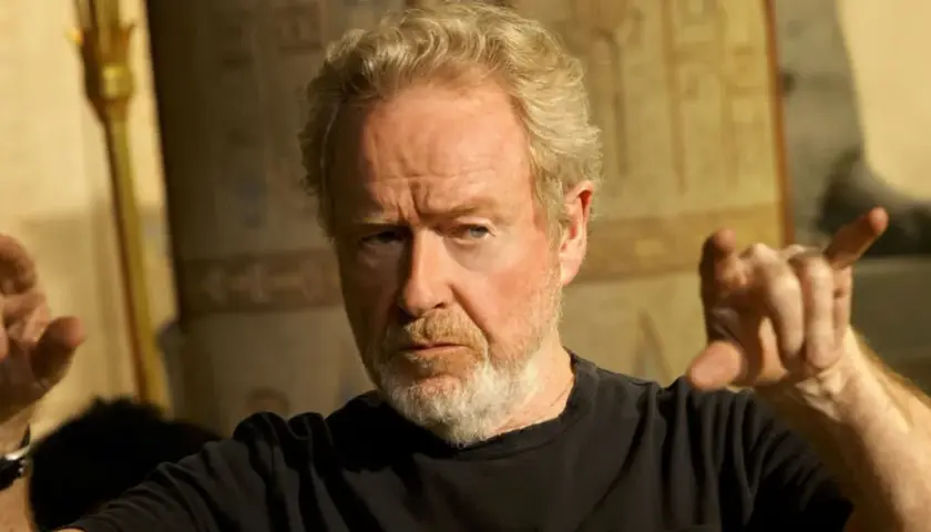 Reżyser Ridley Scott, znany z kultowych filmów, gestykuluje na tle starożytnych dekoracji.