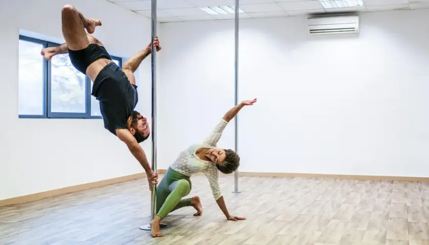 Mężczyzna w powietrzu, kobieta na podłodze. Ich taniec na słupie, niczym kołyska pole dance, tworzy hipnotyzującą choreografię.