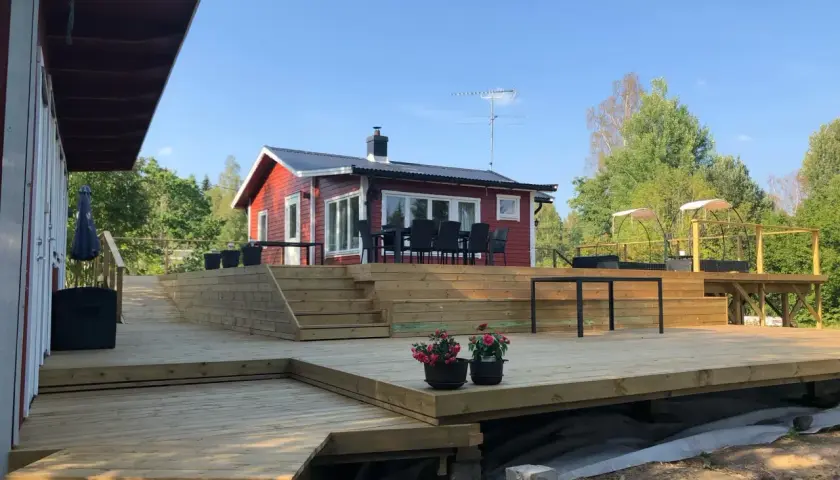 Stor altan runt husknut med trappor och sittplatser. Perfekt för sommarens grillkvällar.
