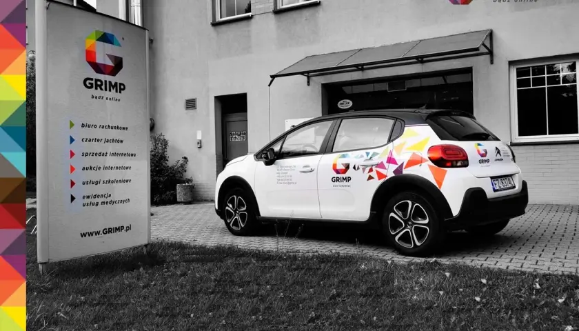 Samochód firmowy GRIMP z kolorowym brandingiem, gotowy do wycofania z firmy. Obok tablica informacyjna z usługami.