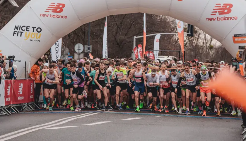 Start biegu na 10 km. Tłum biegaczy pod łukiem startowym New Balance, gotowi do rywalizacji.