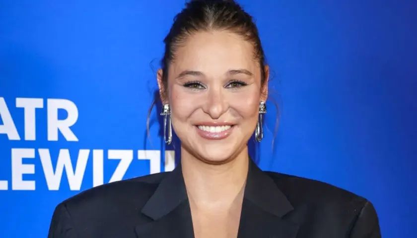 Uśmiechnięta Anna Szymańczyk w czarnej marynarce, z długimi kolczykami. Może właśnie wraca do męża po premierze?