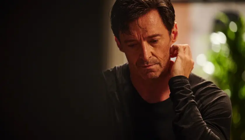 Hugh Jackman w filmie "The Son" zamyślony, z dłonią przy uchu.
