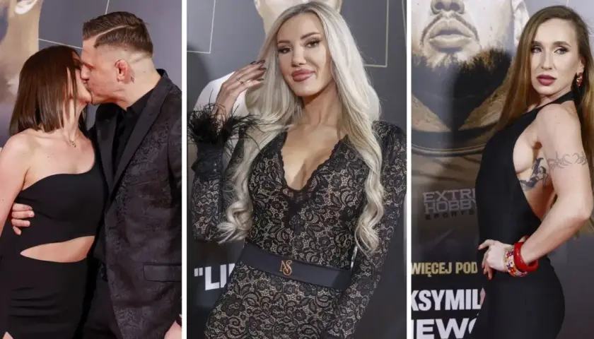 Para na ściance podczas gali Fame MMA. Kobieta w czarnej sukience z wycięciami i mężczyzna w garniturze. Obok dwie inne kobiety w eleganckich kreacjach.