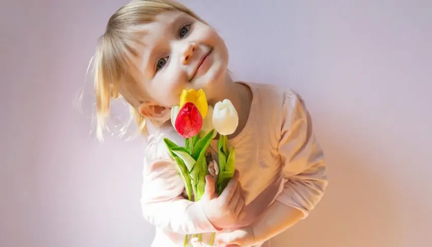 Uśmiechnięta dziewczynka z bukiecikiem tulipanów, jakby czytała krótki wierszyk dla mamy.