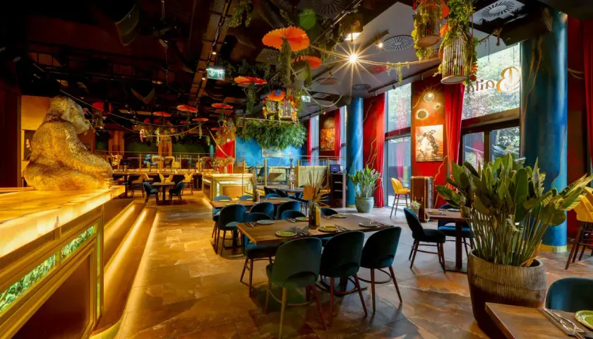 Egzotyczne wnętrze restauracji w Warszawie, z wielką złotą gorylicą przy barze i bujną roślinnością. Idealne miejsce na dobre jedzenie Warszawa.