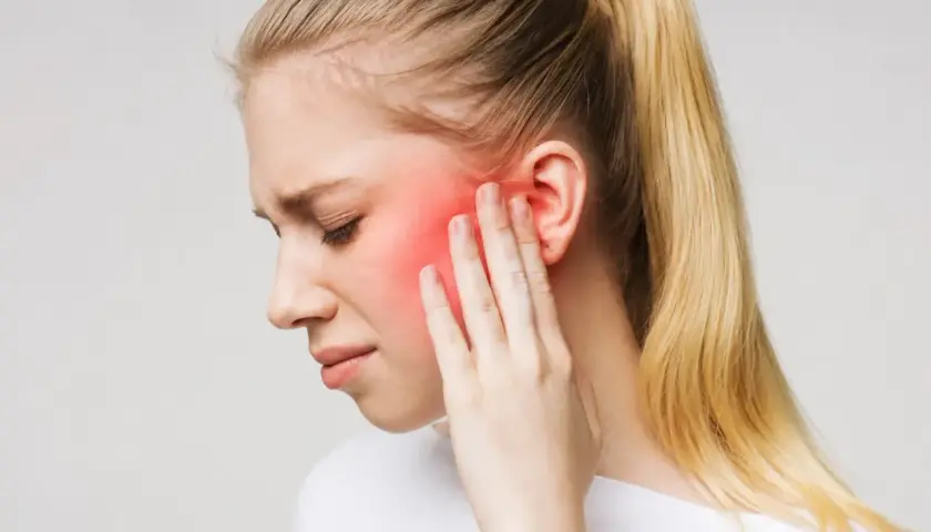 Donna con dolore al viso, area rossa indica possibile nevralgia denti o infiammazione.