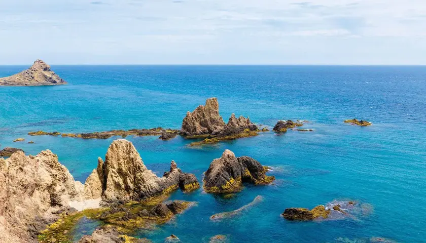 Formaciones rocosas emergen del mar turquesa en el arrecife de las sirenas Almería, un paisaje idílico.