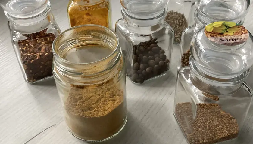 Słoiczki z przyprawami: płatki chili, kurkuma, kmin rzymski, kolendra, gorczyca i inne, idealne do przygotowania aromatycznego curry.