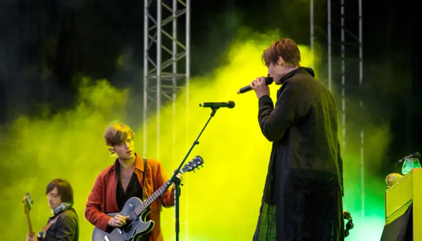 Mando Diao konsert med rök och ljus. Sångaren med mikrofon och gitarristen i röd jacka.