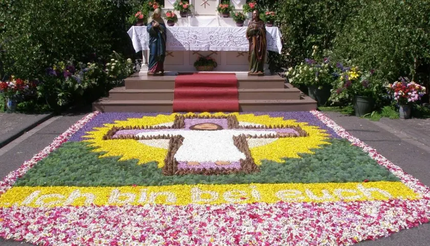 Ein Blumenteppich mit Kreuz und Schriftzug "Ich bin das Brot" erinnert an den Fronleichnam Ursprung.