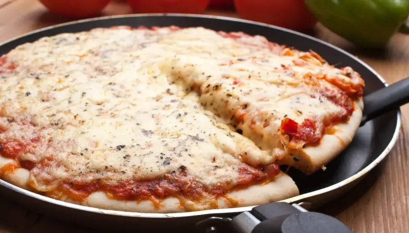 Pyszna pizza z patelni, z ciągnącym się serem i aromatycznymi ziołami, gotowa do podania.