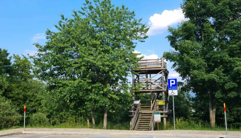 Drewniana wieża widokowa Szczerbanówka z widocznymi schodami i parkingiem.
