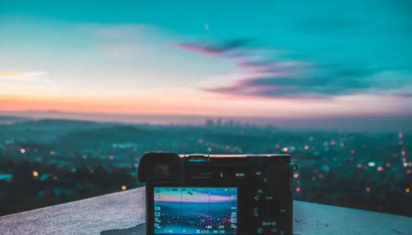 Aparat fotograficzny na tle miejskiego krajobrazu o zachodzie słońca. Wspaniałe światło w fotografii uchwycone w kadrze.