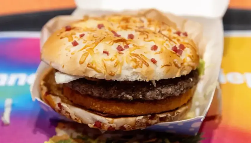 Apetyczny zestaw drwala kcal: soczysty burger z podwójną wołowiną, chrupiącym plackiem ziemniaczanym i bułką posypaną serem i kawałkami boczku.